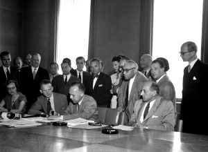 Twaalf staten ondertekenden op 28 juli 1951 de Conventie omtrent de status van vluchtelingen, tijdens de Wereldconferentie omtrent vluchtelingen en staatlozen in Genève. De ondertekenende landen waren Oostenrijk, België, Colombia, Denemarken, Luxemburg, Nederland, Noorwegen, Zweden, Zwitserland en Liechtenstein, het Verenigd Koninkrijk en Joegoslavië. Op de foto zien we van links naar rechts: John Humphrey (Director of the Human Rights Division), Knud Larsen (Deense voorzitter van de Conferentie) en dr. G.J. Van Heuven Goedhart (Hoge Commissaris voor de Vluchtelingen  – UN Photo/ES